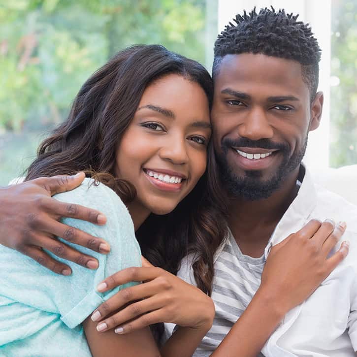 Illustration: Couple on a sofa, man on the left, woman on the right; he holds her shoulder as she leans in, touching his face, both smiling at the camera.