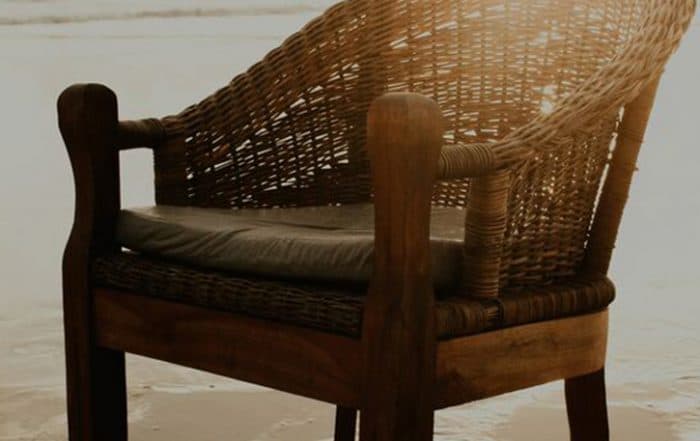 Illustration: Wood and cane chair on beach sand, with the sun rising just above it and the ocean in the background.