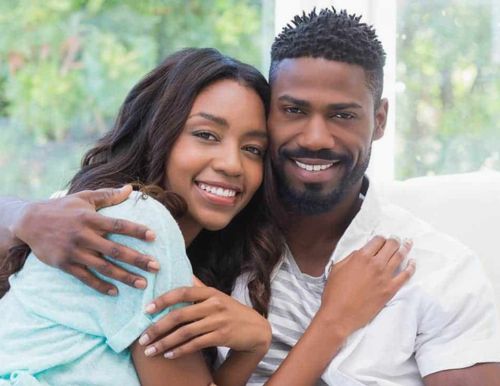 Illustration: Couple on a sofa, man on the left, woman on the right; he holds her shoulder as she leans in, touching his face, both smiling at the camera.