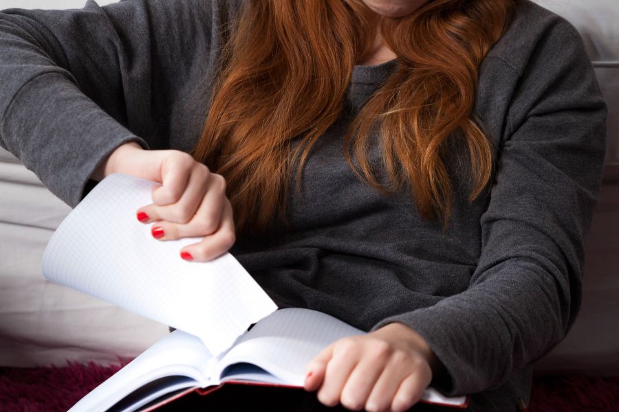 Illustration: An image of a woman tearing pages from a diary